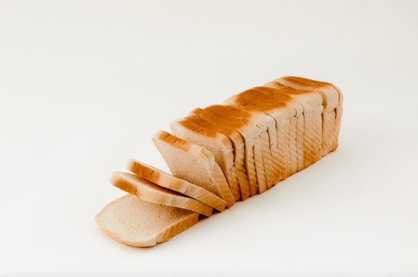 Photograph of a loaf of sliced white bread on a white background